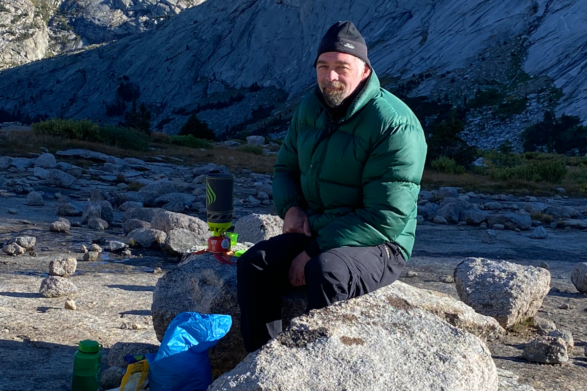 A backcountry camp meal with stove, food, and water on the granite