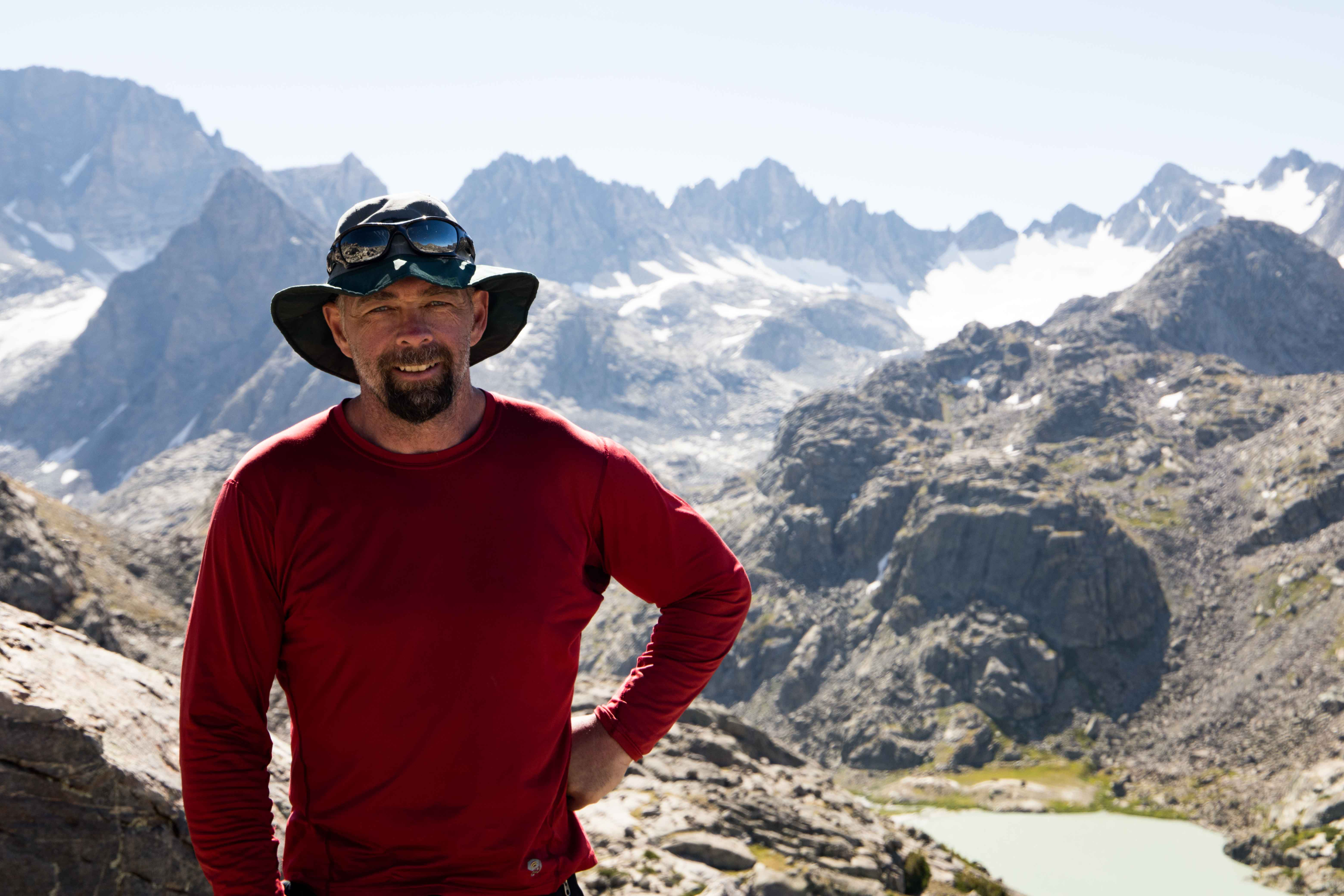 Trent standing on a granite ridge with the Wind River peaks behind him